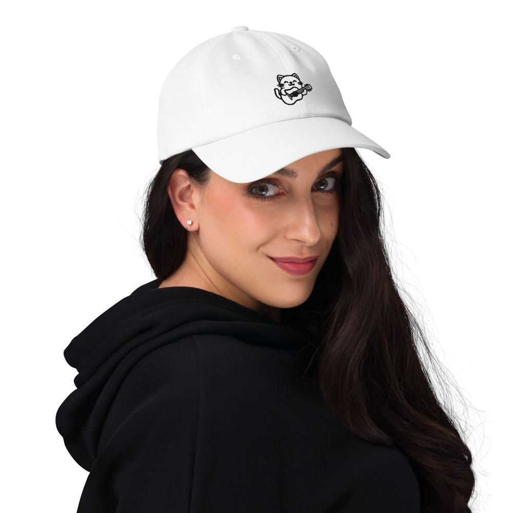 Eine weibliche Person trägt ein gesticktes Dad Hat mit dem Design einer Katze, die Gitarre spielt. Das Accessoire kombiniert Tierliebe mit Musikgenuss, ideal für einen modischen und persönlichen Stil.